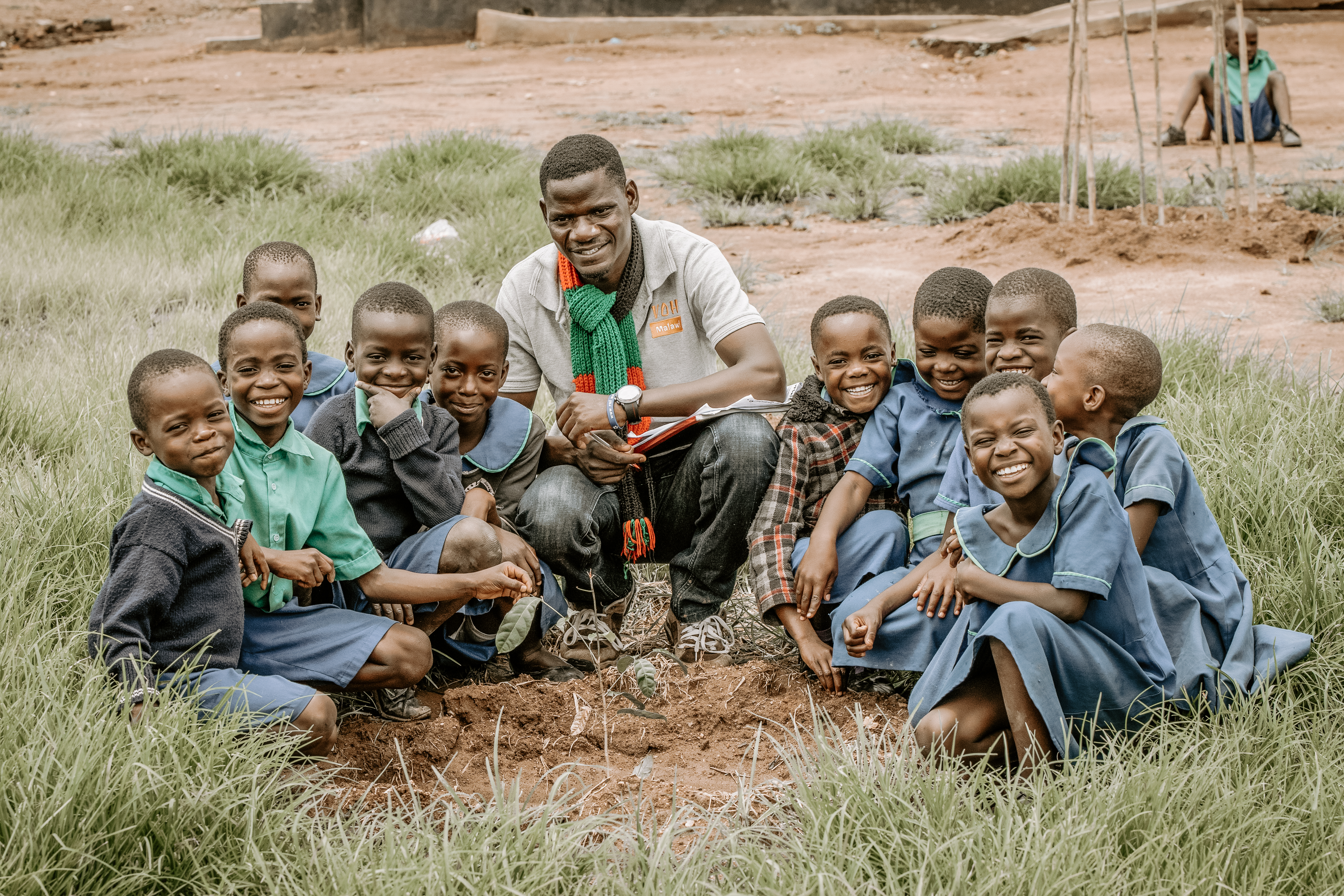 A group of students and their teacher planting a tree