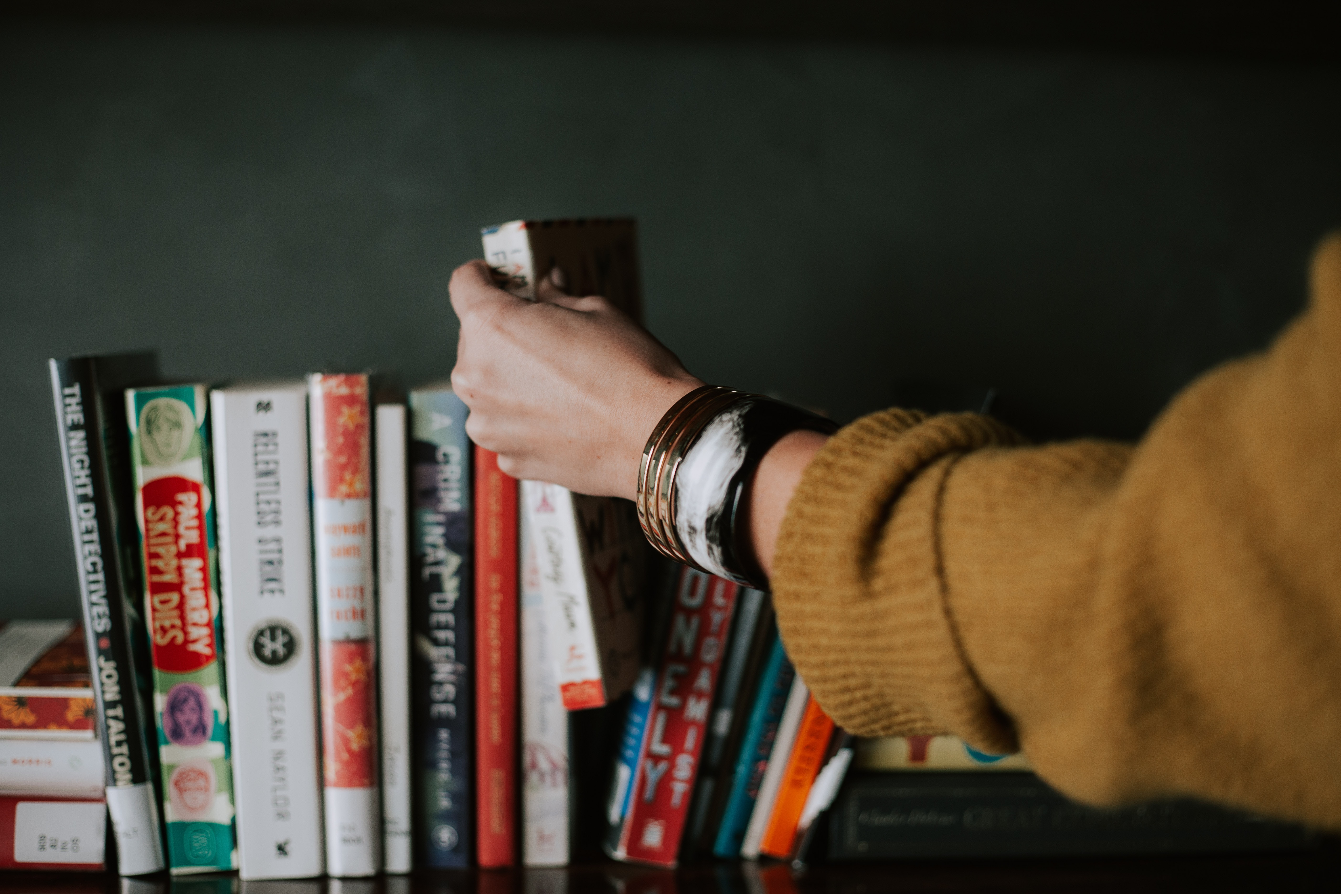 Photo by Christin Hume on Unsplash of a girl reaching for a book