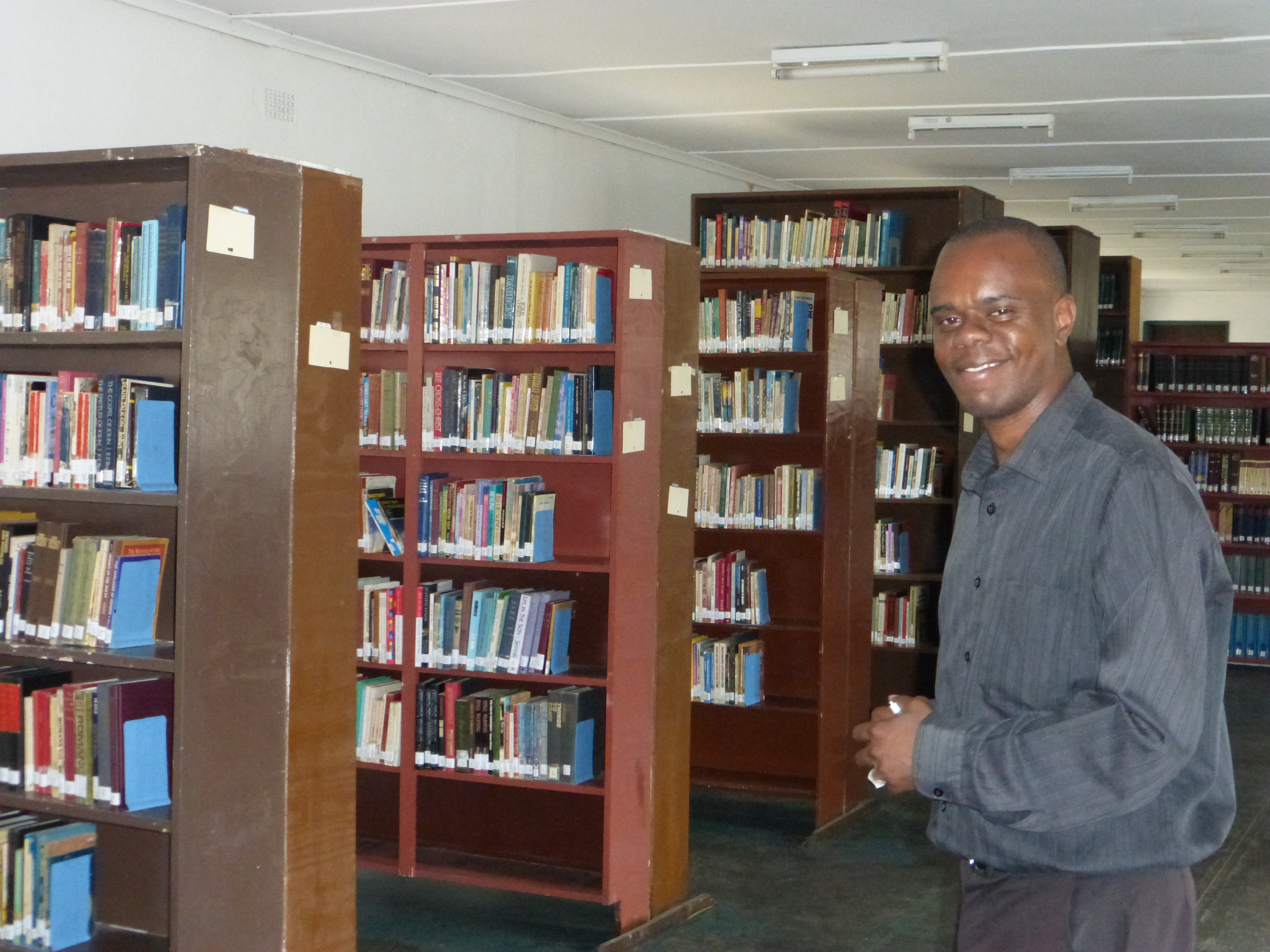 Man in front of an isle of bookshelves