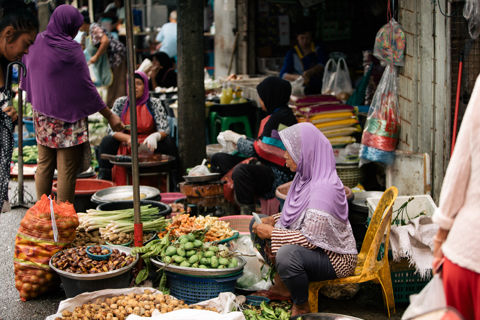 Photo of a lady sitting in front of her basket at a farmer's market by Imagine Thailand