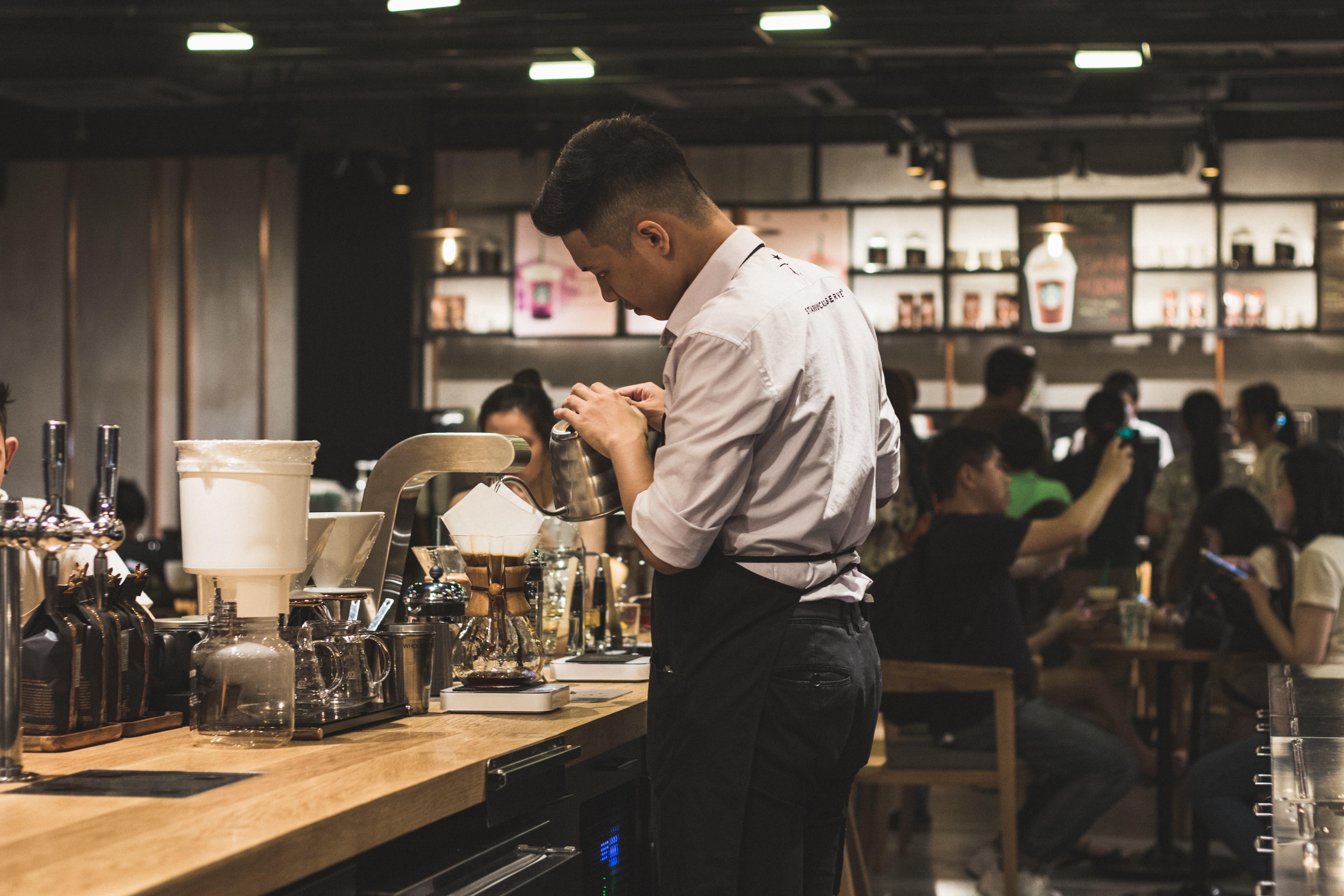 Photo by Quan Le on Unsplash of a Barista at a store.