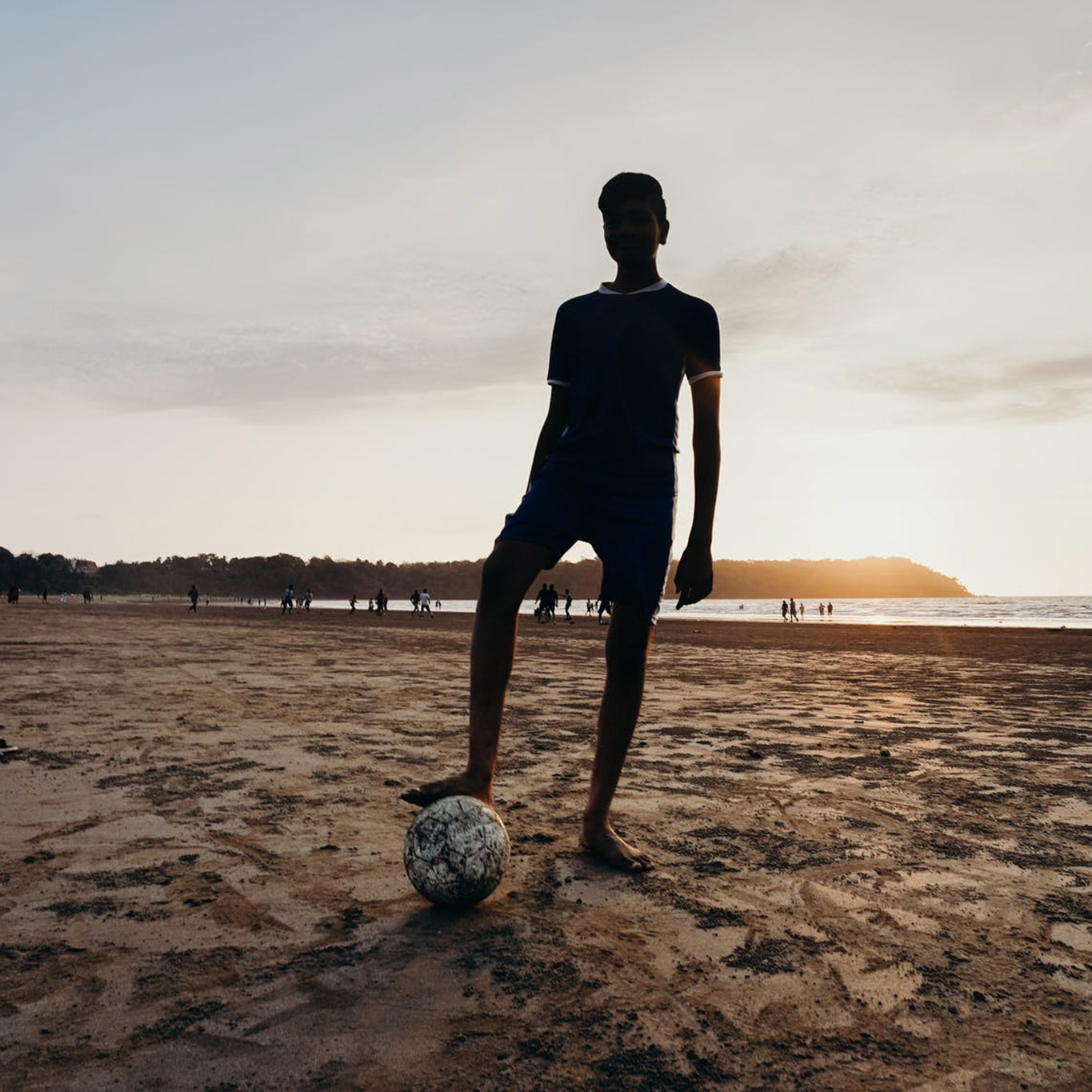 Boy with foot on soccer ball on beach
