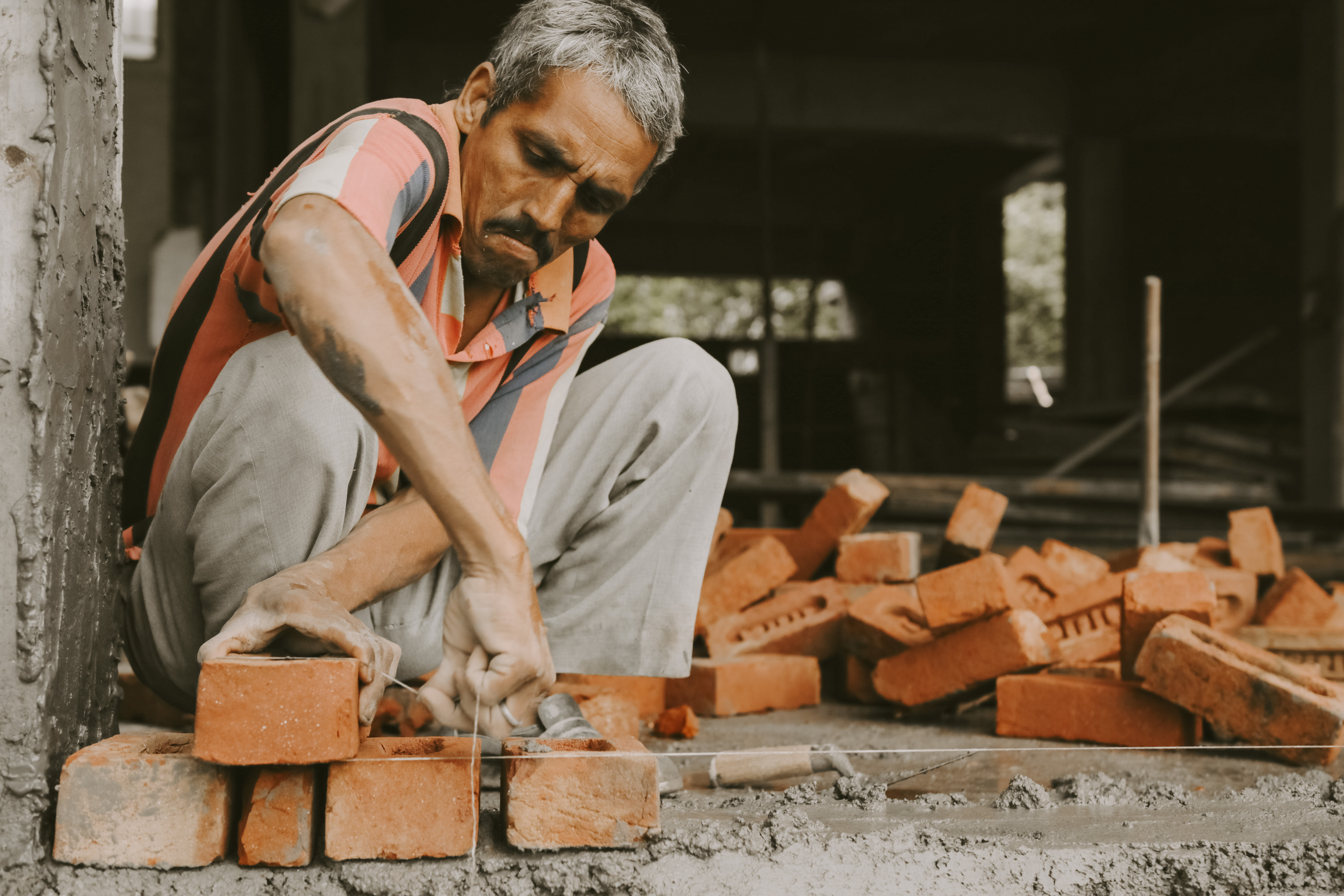 Photo of a male aligning bricks in India