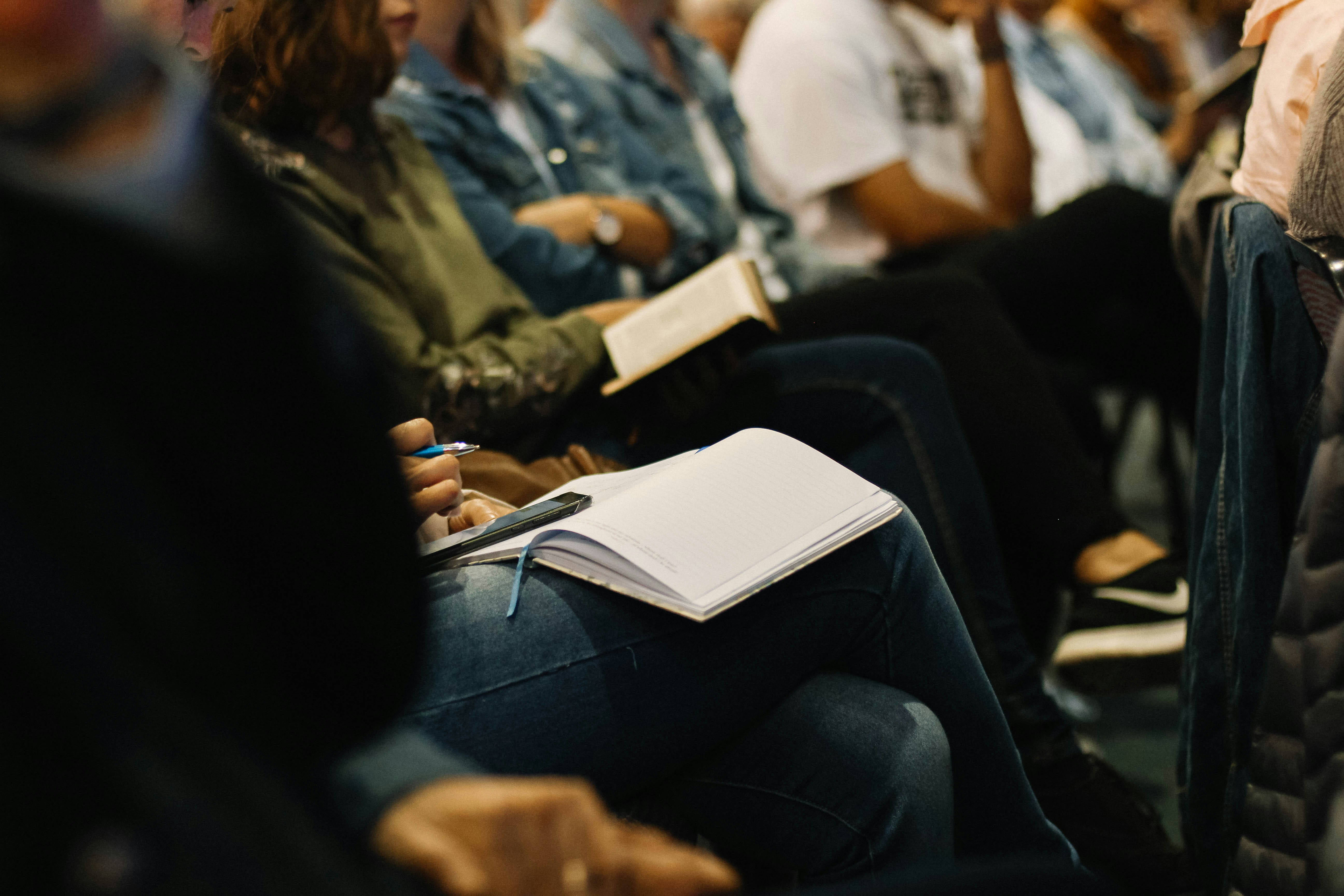 People sitting in a group, some of them with notebooks.